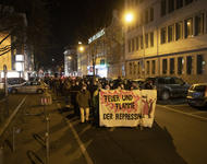 Ein Demonstrationszug bei Dunkelheit in der Rempartstraße. Auf dem Fronttransparent ist ein Drache abgebildet und es steht "Feuer und Flamme der Repression" darauf.