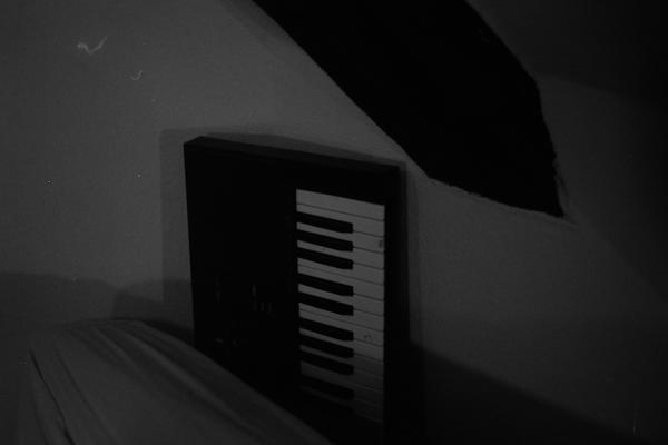 ein keyboard ragt hinter einem sofa hervor. das bild ist schwarz-weiß
